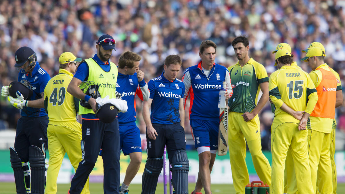 England's captain Eoin Morgan, center, walks from the pitch after being hit on the head off a ball bowled by Australia Mitchell Starc, third right in yellow, during the deciding cricket match of the One Day International series between England and Australia at Old Trafford cricket ground in Manchester, England, Sunday, Sept. 13, 2015. (AP Photo/Jon Super)