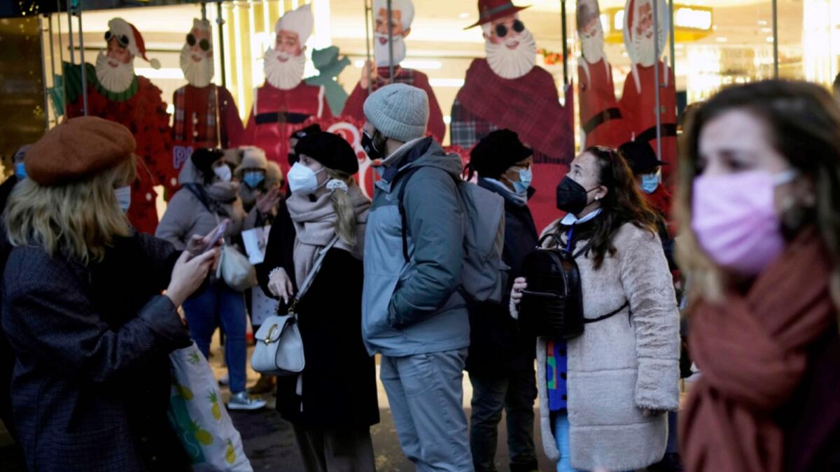 Pedestrians wear masks to prevent the spread of the Covid-19 as they walk past a store decorated as part of Christmas lightings in Paris. — AP