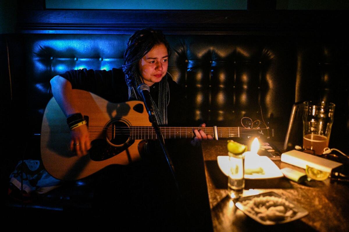 A woman plays guitar in a pub during a blackout in Lviv on December 2, 2022. Photo: AFP