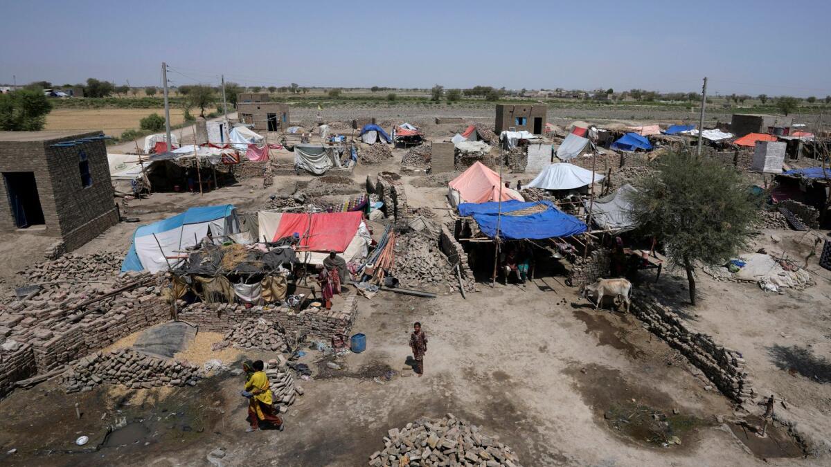 Women walk through their tents set up over the rubble of their damaged homes caused by last year's floods, at a village in Dada, a district of Pakistan's Sindh province, on Wednesday, May 17, 2023. -- AP