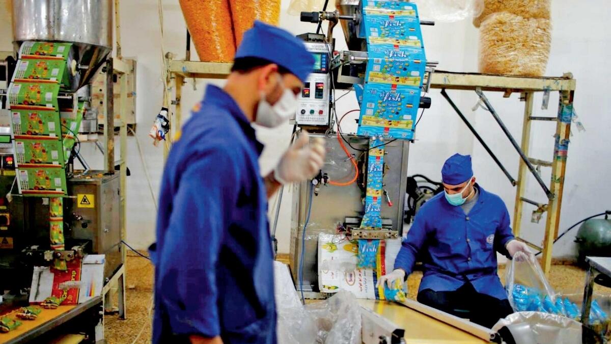 Two Palestinians busy with their work at a snacks and chips factory, east of Gaza City. — Reuters 