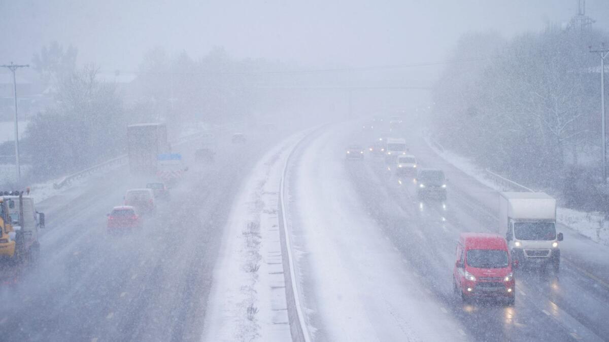 Cars driving through snow on the the M5 motorway near Taunton, England, on Wednesday. — AP