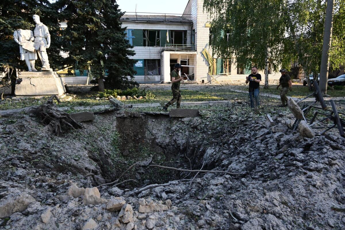 Residents observe the hole and the damage caused in the House of the Culture, in Druzhkivka, south of Kramatorsk, eastern Ukraine, following a suspected missile attack in the early morning of July 9, 2022 (Photo by AFP)