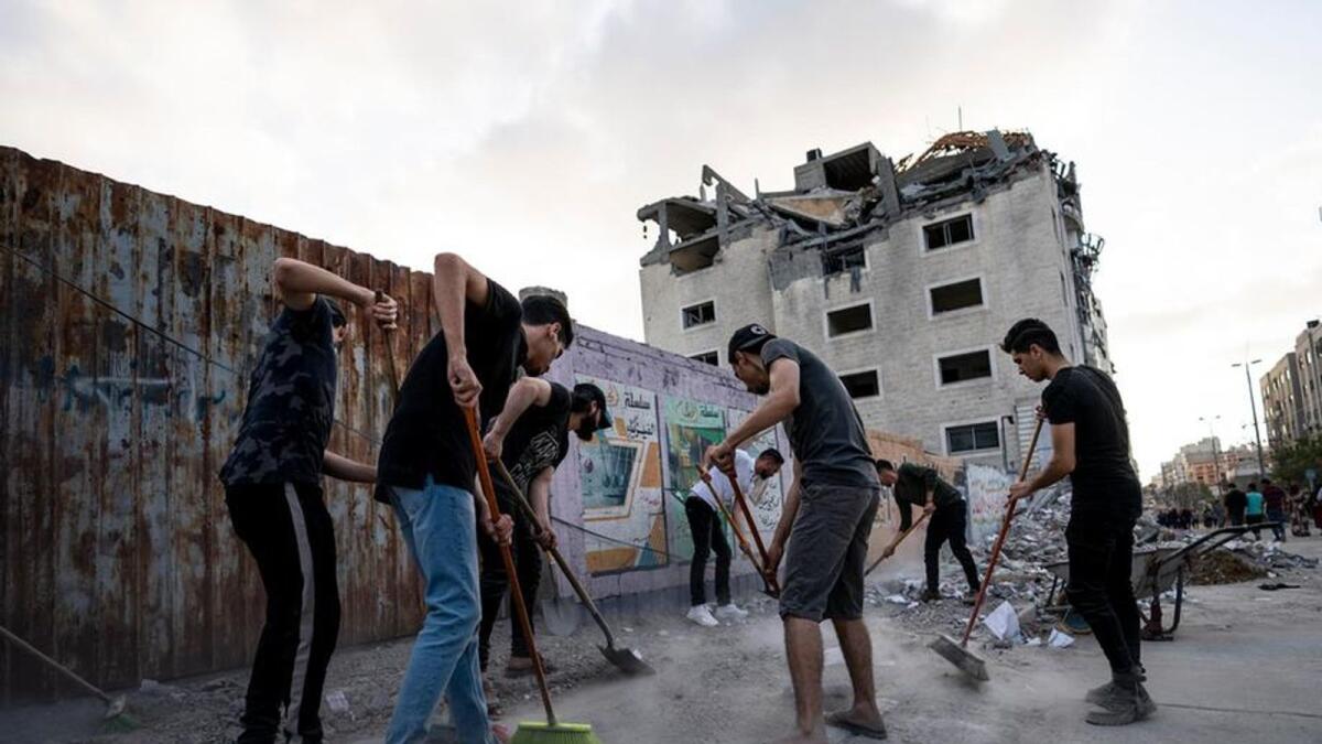 People clean the streets beside a building that was previously damaged in an air-strike following a cease-fire reached after an 11-day conflict, in Gaza City.- AP