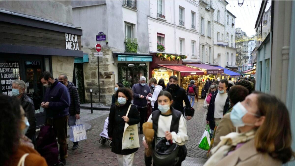 Pedestrians, some wearing protective face masks to prevent the spread of Covid-19, walk in street market, in Paris. — AP