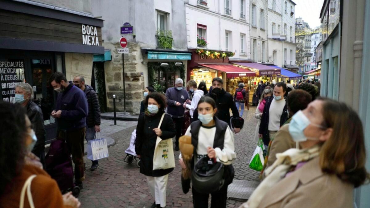 Pedestrians, some wearing protective face masks to prevent the spread of Covid-19, walk in street market, in Paris. — AP