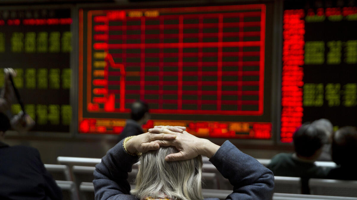 A woman reacts near a display board showing the plunge in the Shanghai Composite Index at a brokerage in Beijing on Thursday. — AP