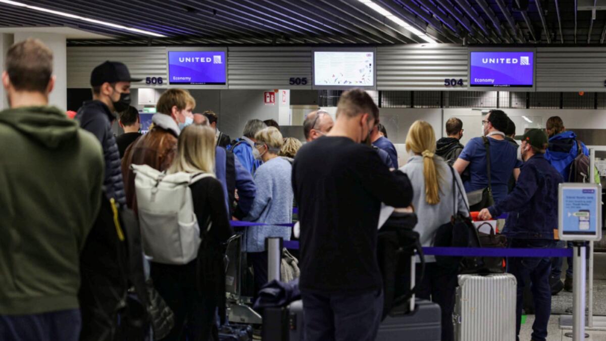 People wait in line to check in for flights to the United States at the airport in Frankfurt. — AFP