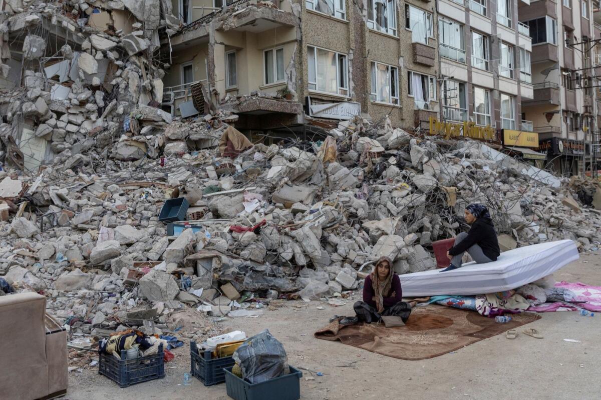 Victims sit outside a destroyed building in the aftermath of the deadly earthquake in Antakya, Hatay province, Turkey. Photo: Reuters