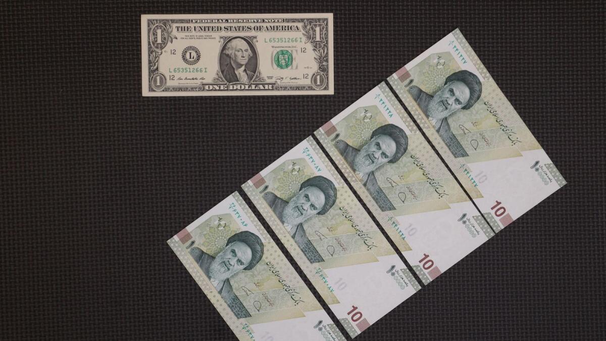 A US one-dollar bill is seen against four 10000 Iranian rial bills in an exchange shop in Tehran. - Reuters