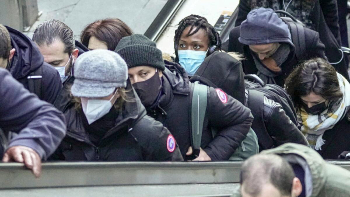 Commuters wearing face masks ride an escalator at La Defense business district in Paris. — AP