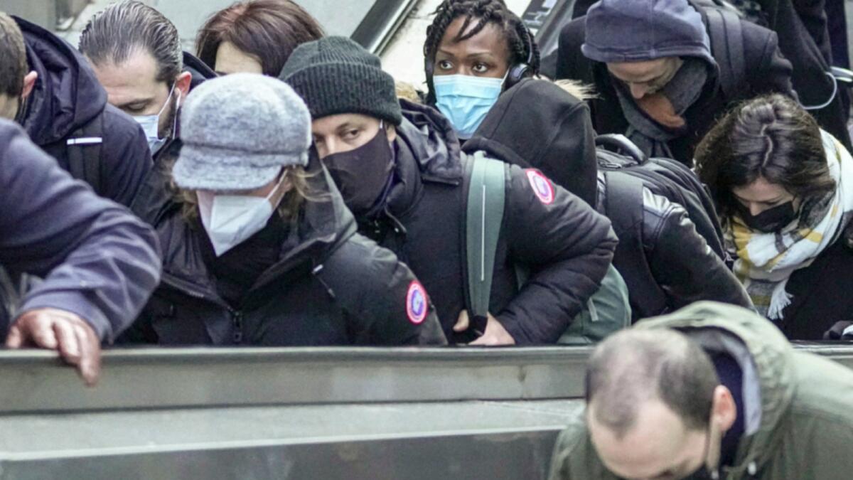 Commuters wearing face masks ride an escalator at La Defense business district in Paris. — AP