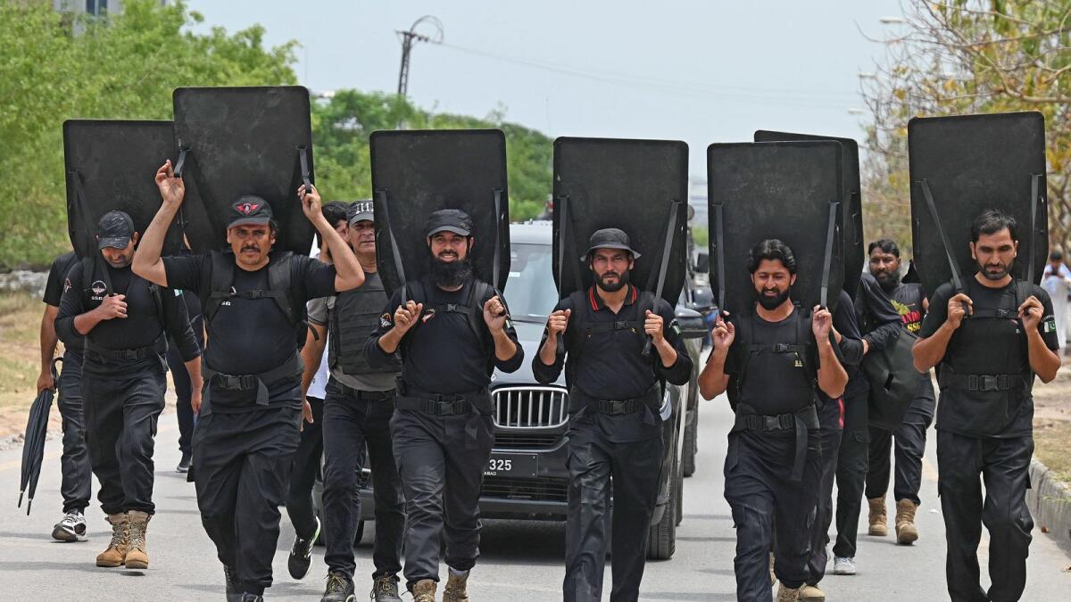 Security personnel with ballistic shields escort a vehicle carrying former Pakistan's prime minister Imran Khan as he leaves after appearing before an anti-terrorism court in Islamabad on Tuesday. — AFP