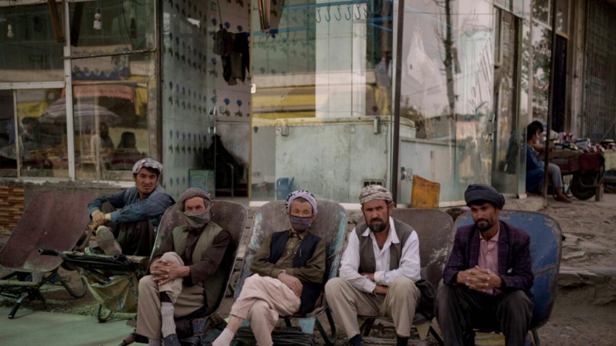 Workers sit on their wheelbarrows as they wait to be hired on the side of the road in Kabul. — AP