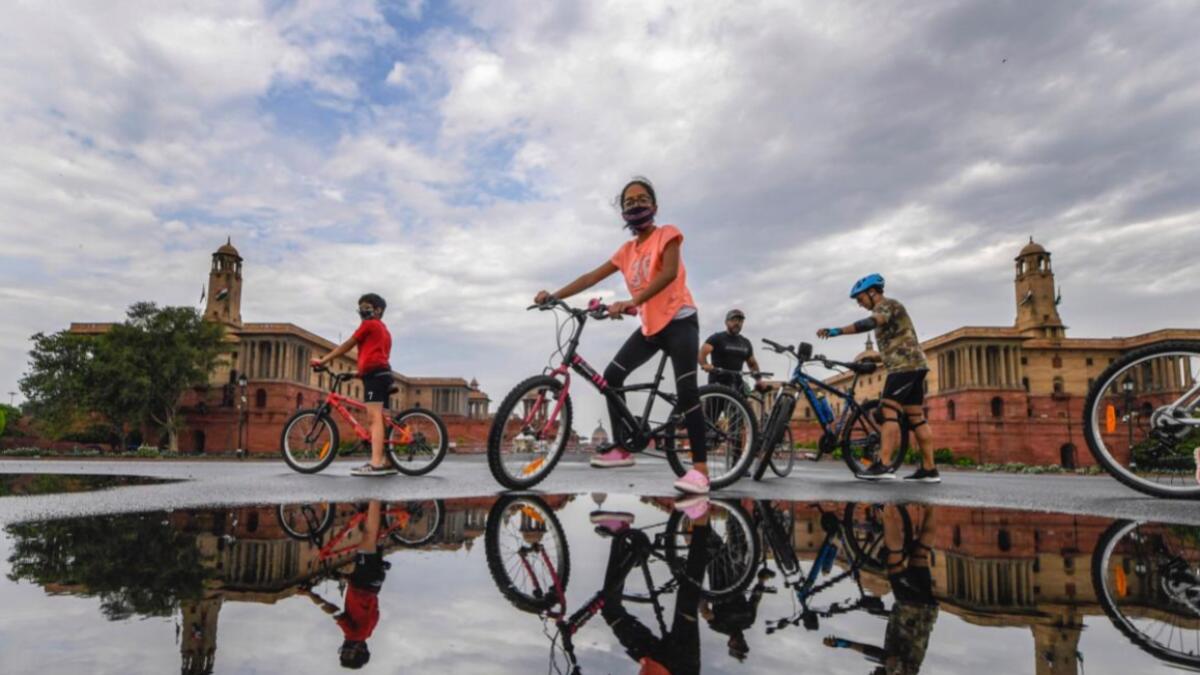 Youngsters ride bicycles at Vijay Chowk as monsoon clouds hover in the sky, in New Delhi on Sunday, July 5, 2020. Photo by PTI