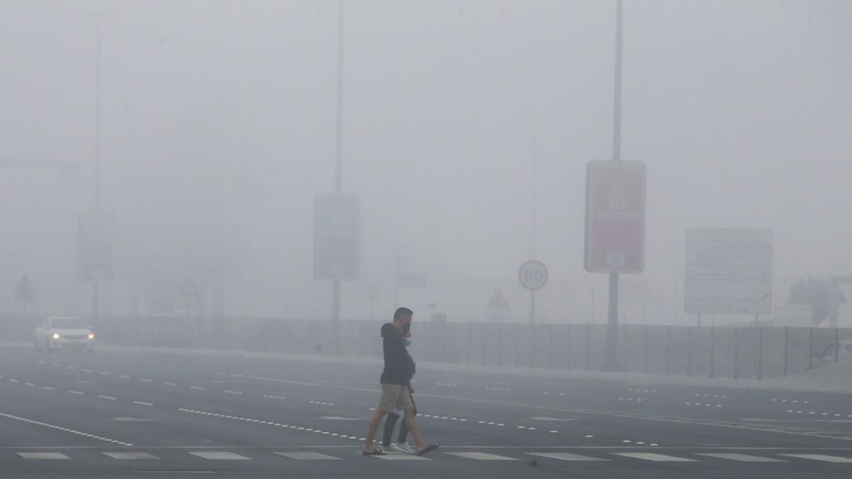 Residents cross a road in Abu Dhabi on a foggy morning. — Photo by Ryan Lim
