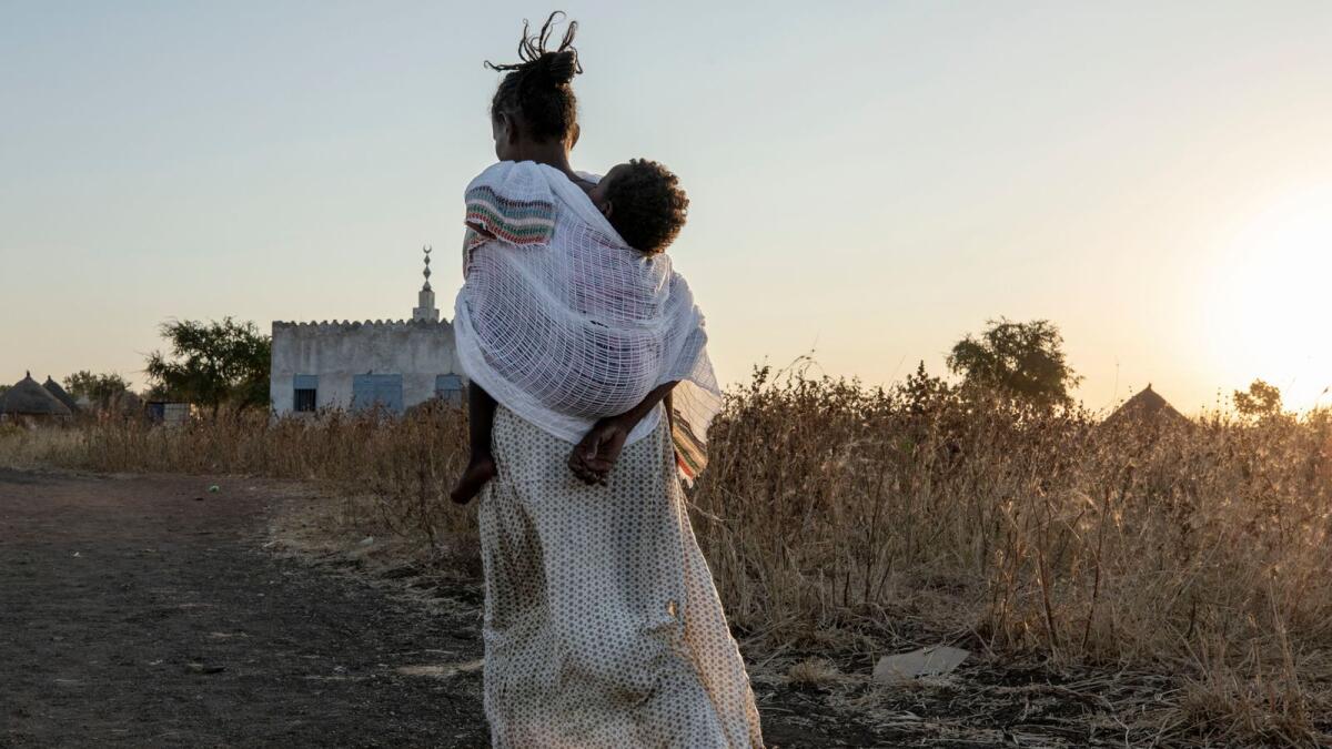 A Tigrayan woman who fled the conflict in Ethiopia's Tigray region, carries her baby to attend Sunday Mass at a church, near Umm Rakouba refugee camp in Qadarif, eastern Sudan, on Sunday.