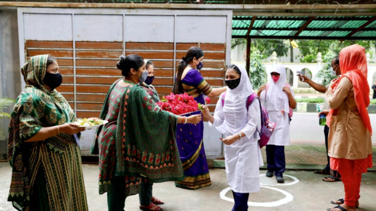 Teachers welcome students with roses at a school in Dhaka after schools in Bangladesh reopened two weeks ago following long Covid-19 lockdown. — Reuters