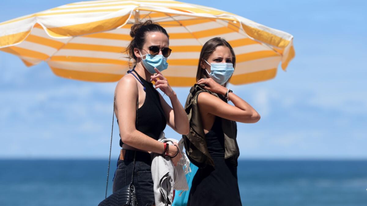 People wearing a protective face mask walk along the beach, in Biarritz, amid the crisis linked with the Covid-19 pandemic caused by the novel coronavirus. Outdoor mask-wearing has also been made mandatory in parts of the northern region of Mayenne, as well as the popular coastal holiday destinations of Biarritz, Saint-Malo and Le Touquet. Photo: AFP