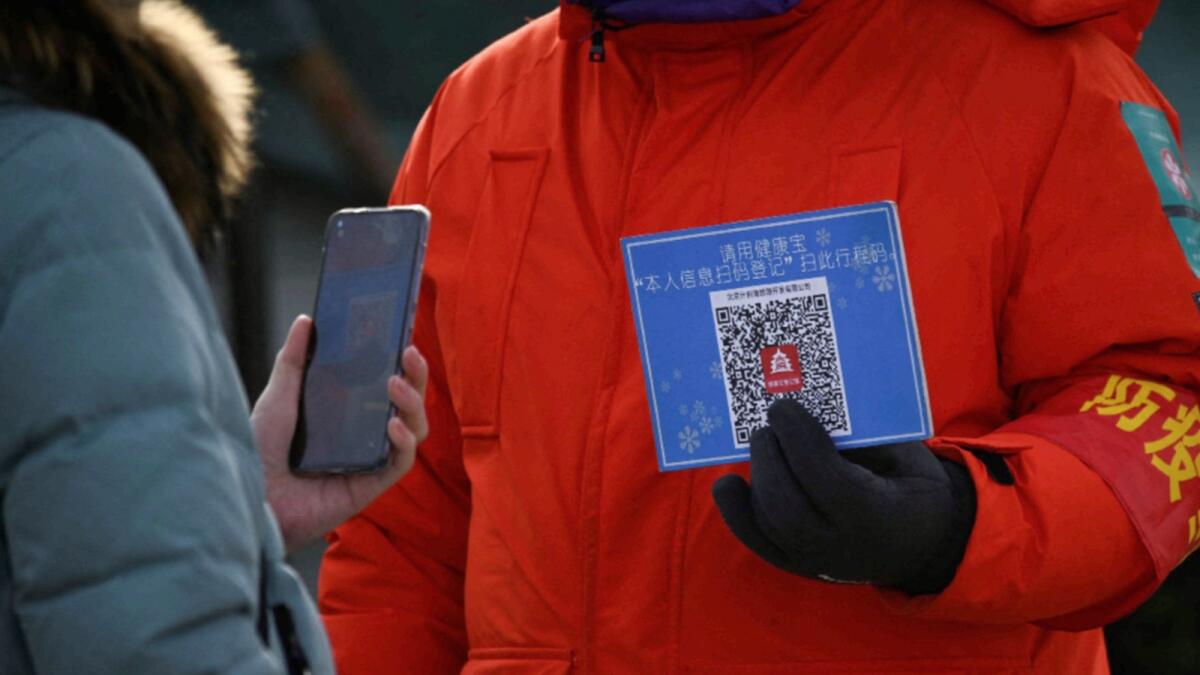 A woman uses her mobile phone to scan a QR code for health registration before entering an outdoor ice rink in Beijing. — AFP
