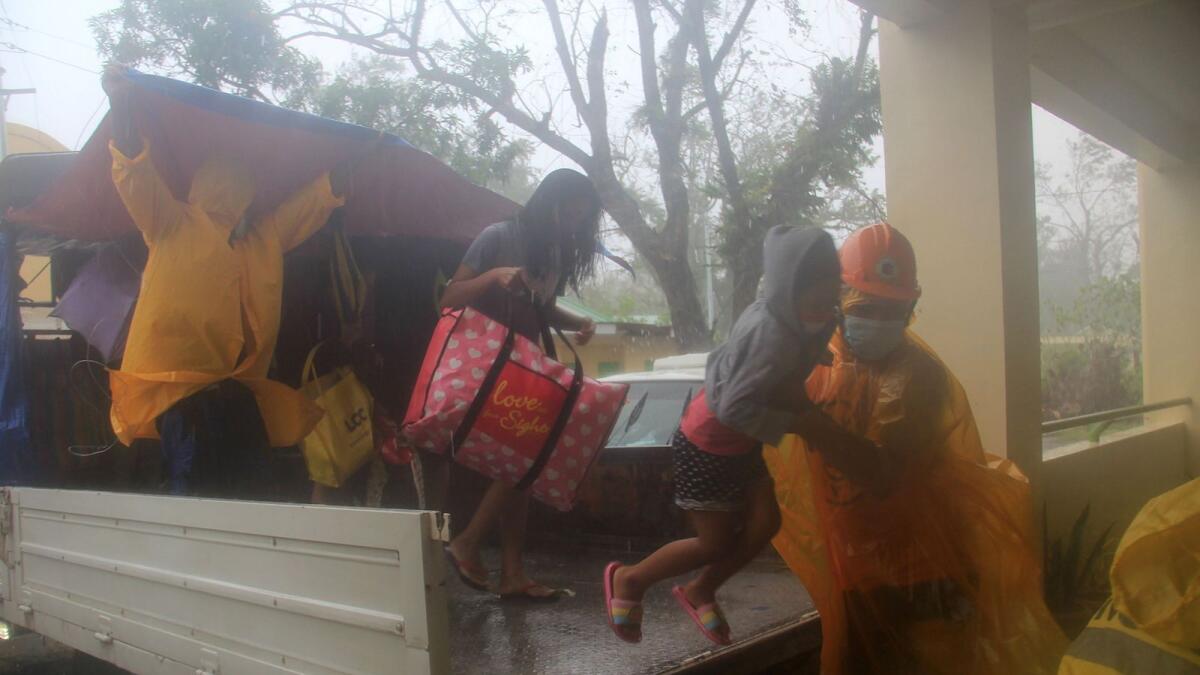 Rescuers help residents disembark from a vehicle during the evacuation in Legazpi City, Albay province ahead of the landfall of Tropical Storm Vamco.