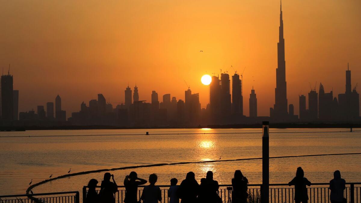 People watch the sunset over the skyline, with Burj Khalifa at right, in Dubai. Three largest GCC economies – Saudi Arabia, UAE and Qatar – to see the strongest non-oil recoveries in 2021. — AP file photo