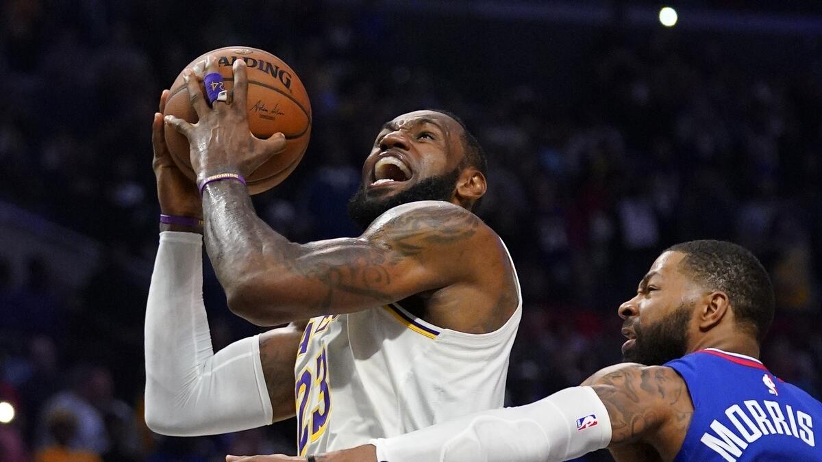 Los Angeles Lakers forward LeBron James, left, shoots as Los Angeles Clippers forward Marcus Morris Sr. defends (AP)