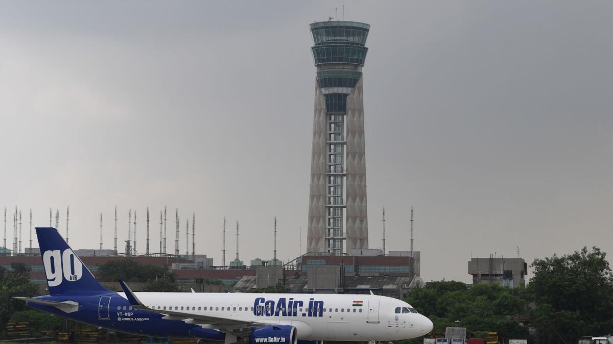 A GoAir plane taxis past a control tower at Indira Gandhi International Airport in New Delhi. Since the resumption of operations on May 25, domestic air traffic continued to sequentially improve in December 2020. — AFP file