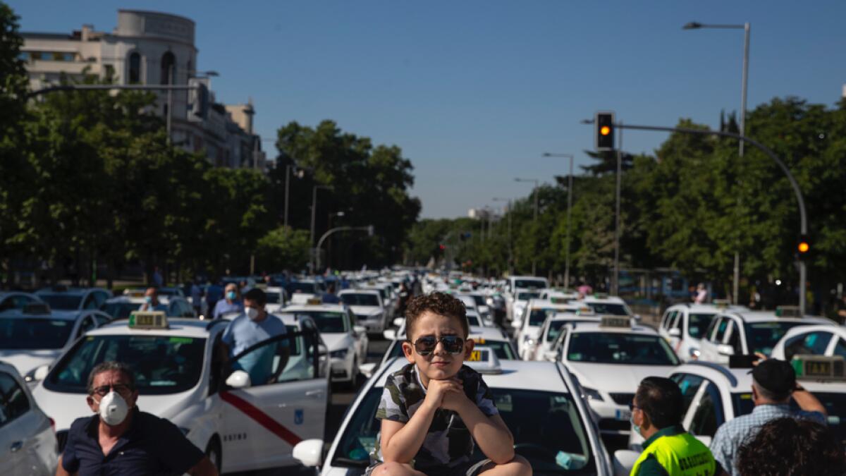 A child sits on the roof of a taxi during a taxi driver protest in downtown Madrid, Spain. Taxi drivers are demanding assistance due to lack of clients and private hire. Photo: AP