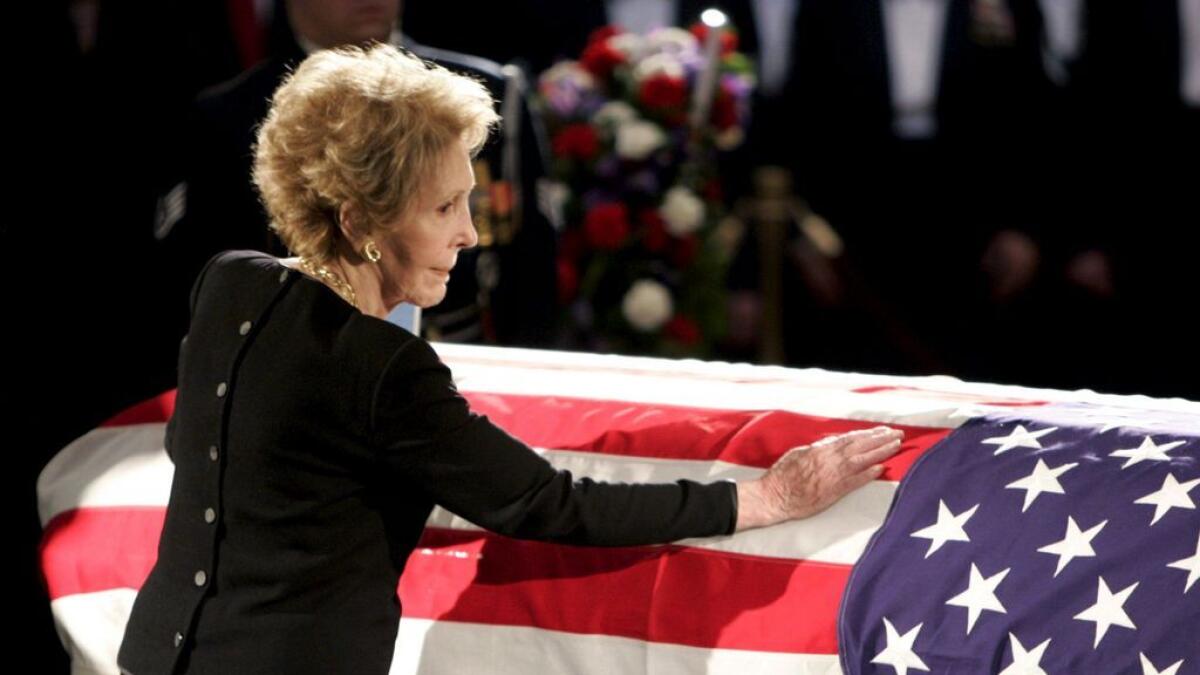 Nancy Reagan touches the casket of her husband, former US President Ronald Reagan, as it lies in state in the rotunda of the United States Capitol in Washington.- Reuters file photo
