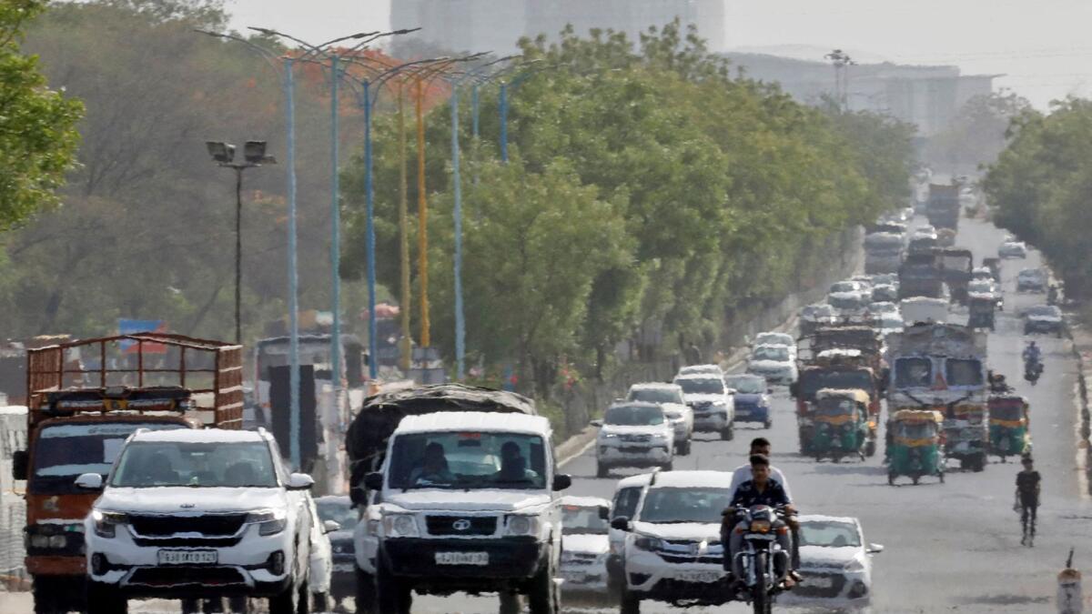 Traffic moves on a road in a heat haze during hot weather on the outskirts of Ahmedabad. — Reuters file