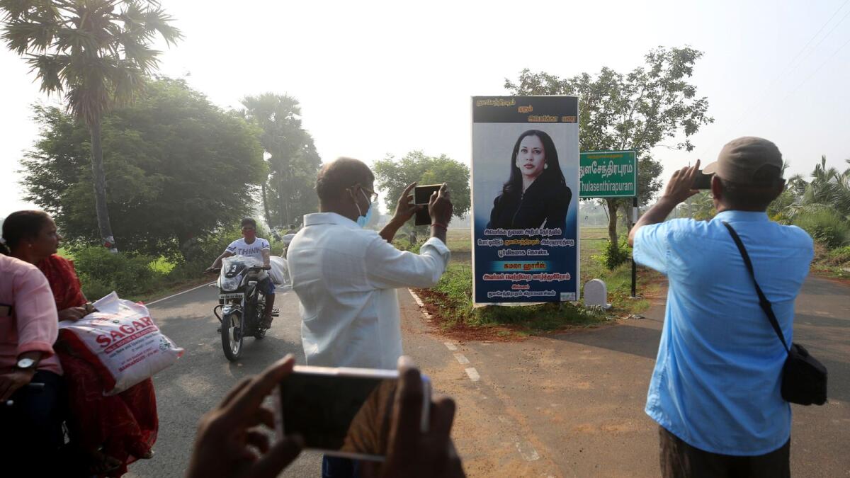 People take pictures of a billboard featuring Kamala Harris at a crossing in Thulasendrapuram village, south of Chennai, Tamil Nadu state, India. AP