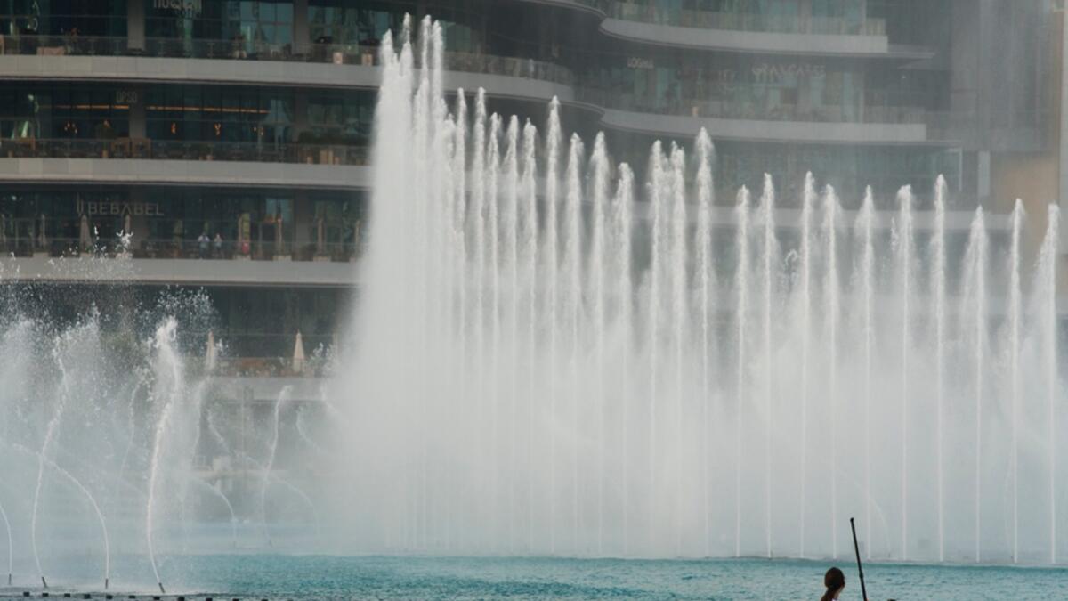 A woman on a paddle board takes a selfie while the Dubai Fountain dances behind her during a race near the Burj Khalifa, the world's tallest building, in Dubai, UAE. Photo: AP