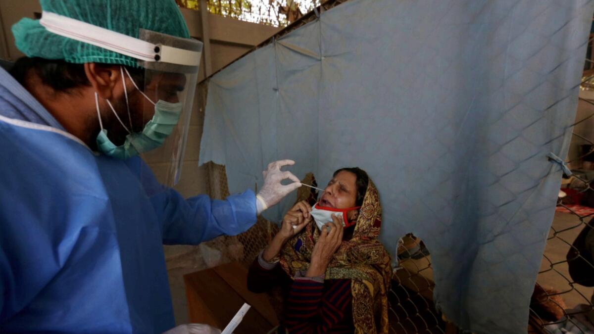A healthcare worker takes a nasal swab sample from a woman at a Covid-19 testing facility at a hospital in Karachi. — AP