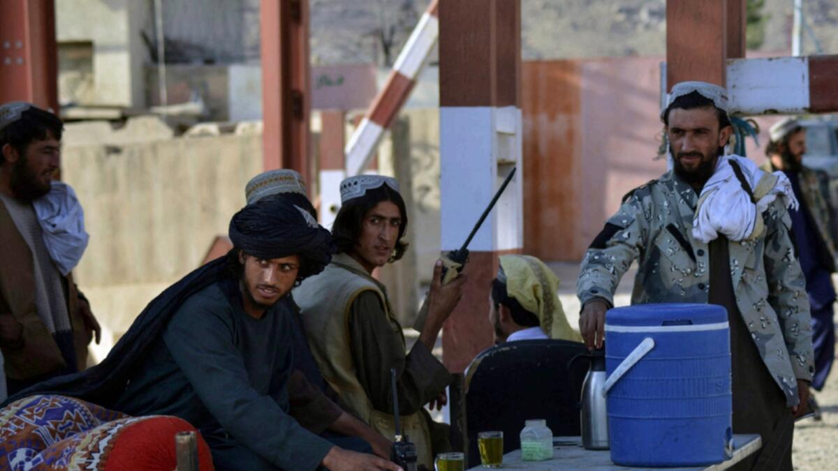 Taliban members guard an entrance gate of the Panjwai district police headquarters in Kandahar province. — AFP