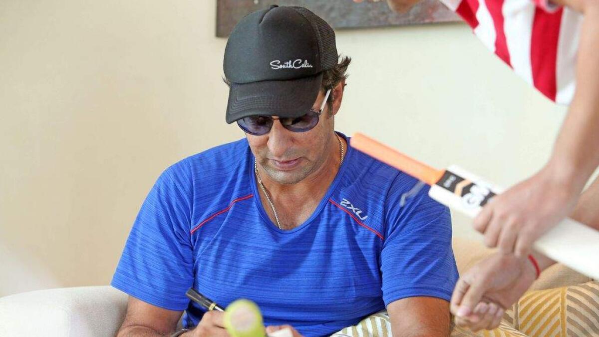 Wasim Akram autographs a bat during an interview in Dubai on Saturday, October 10, 2015.