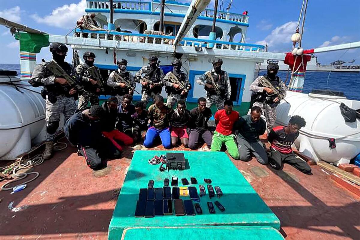 Indian commandos stand guard with a group of detained pirates after the Indian Navy freed an Iranian fishing vessel hijacked by Somali pirates, off the Somali coast, some 850 nautical miles (1,574 kilometres) west of the Indian city of Kochi. — AFP