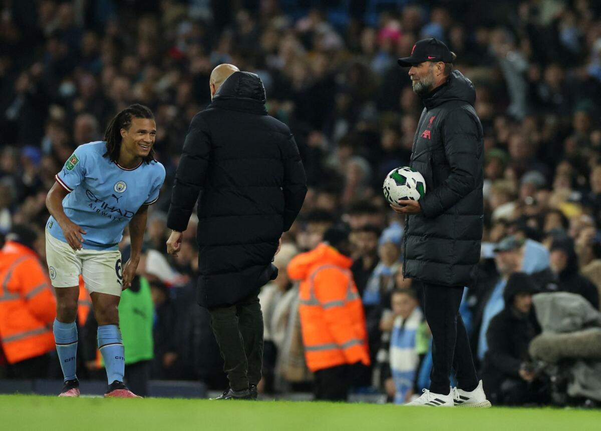 Manchester City manager Pep Guardiola talks to Nathan Ake as Liverpool manager Juergen Klopp looks on. (Reuters)