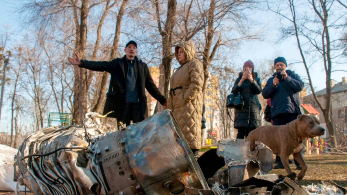 People stand next to fragments of military equipment on the street in the aftermath of an apparent Russian strike in Kharkiv. — AP