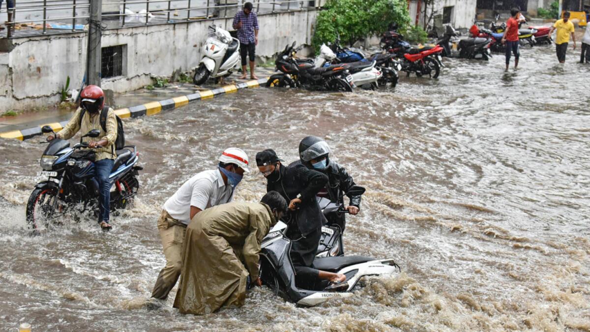 Traffic cops help a motorist pull his bike through a waterlogged street, in Hyderabad, Telangana, Indian. Photo: PTI