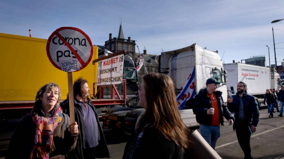 Demonstrators talk as some 20 trucks blocked one entrance to the government buildings, rear, in The Hague, Netherlands. — AP