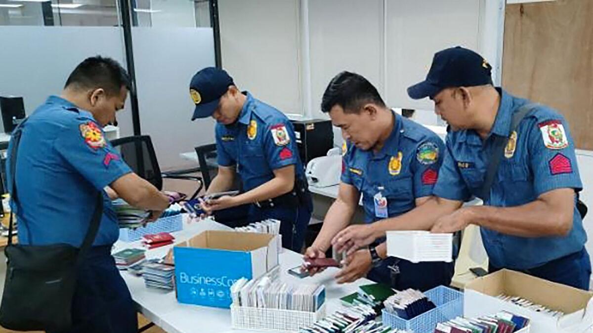 Policemen inspecting documents and passports after a raid inside a freeport zone in Mabalacat City, in Pampanga province, north of Manila. — AFP