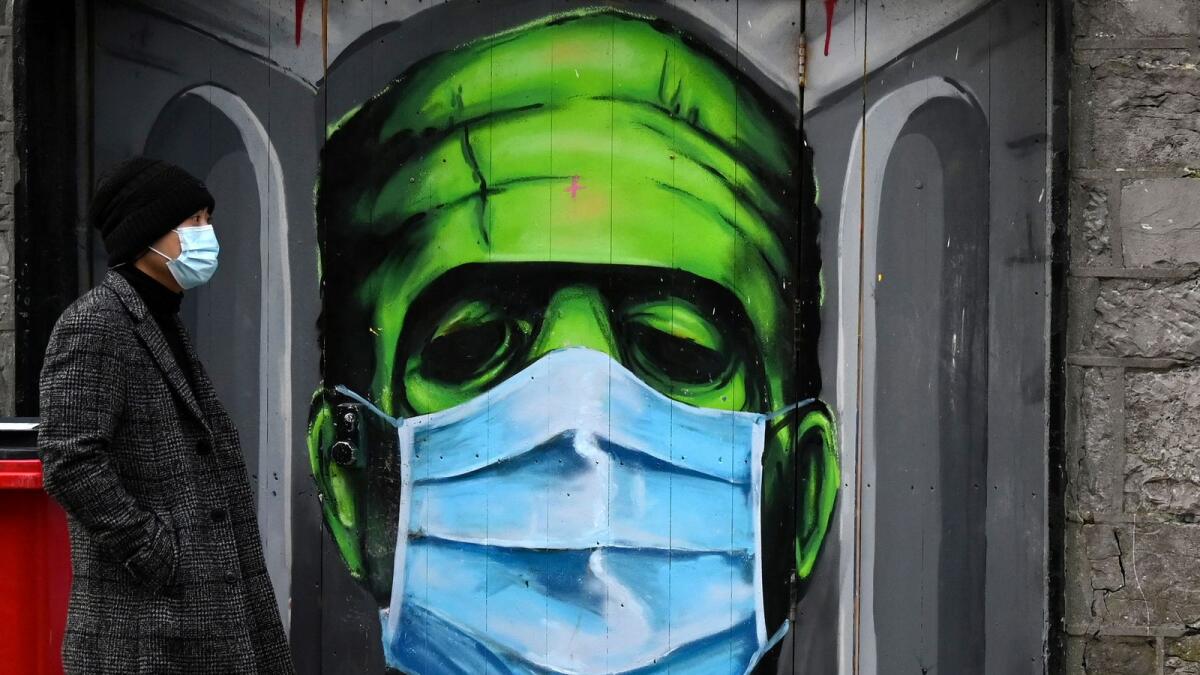 A man walks past a graffiti of a Frankenstein wearing a protective face mask on a doorway amid the spread of the coronavirus disease (COVID-19) pandemic, in Galway, Ireland, December 22, 2020.
