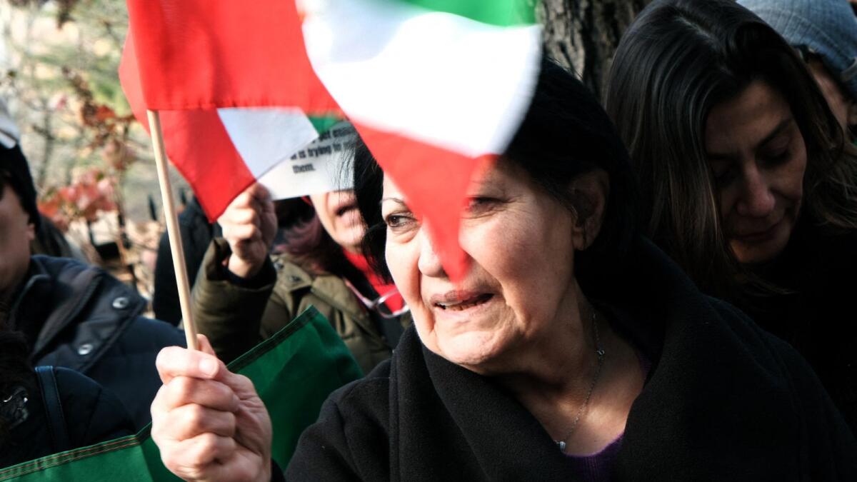 A woman joins protestors as they gather outside of an Iranian diplomat's residence to denounce the Iranian government and the recent execution of a protester in New York City. - AFP