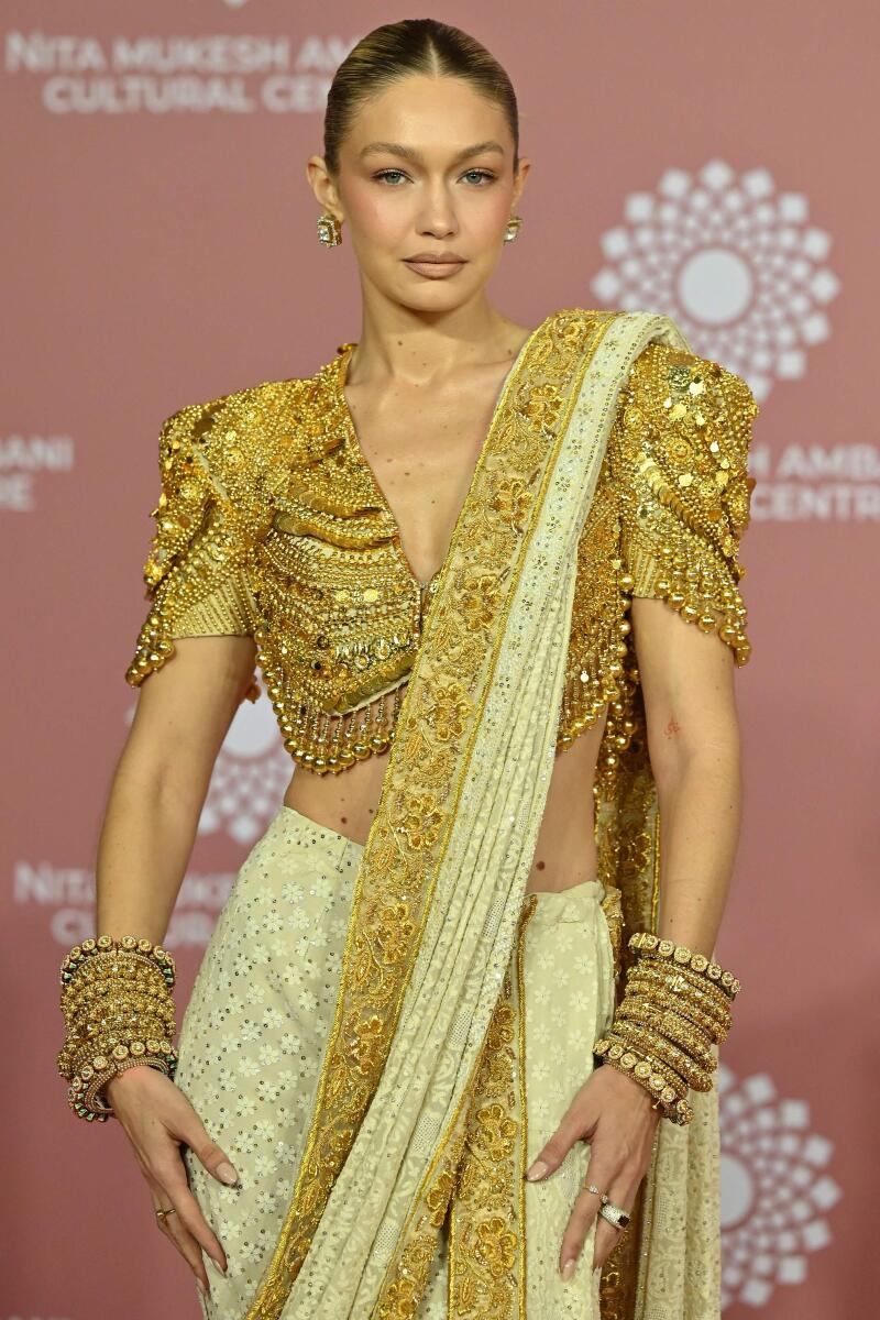 Gigi Hadid stunned in a white sari with golden work, styled with an embellished statement blouse, and accessorised with bangles and ethnic earrings