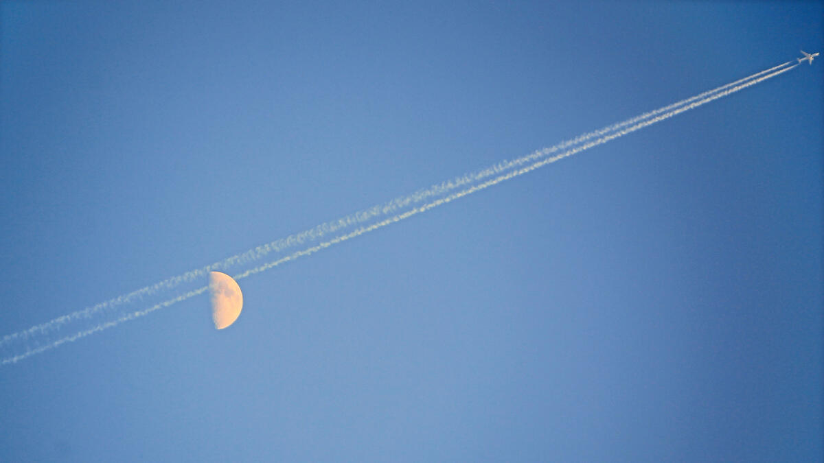 A plane flies past rising moon in Dubai leaving its trail across the sky.-  Photo by Neeraj Murali/Khaleej Times