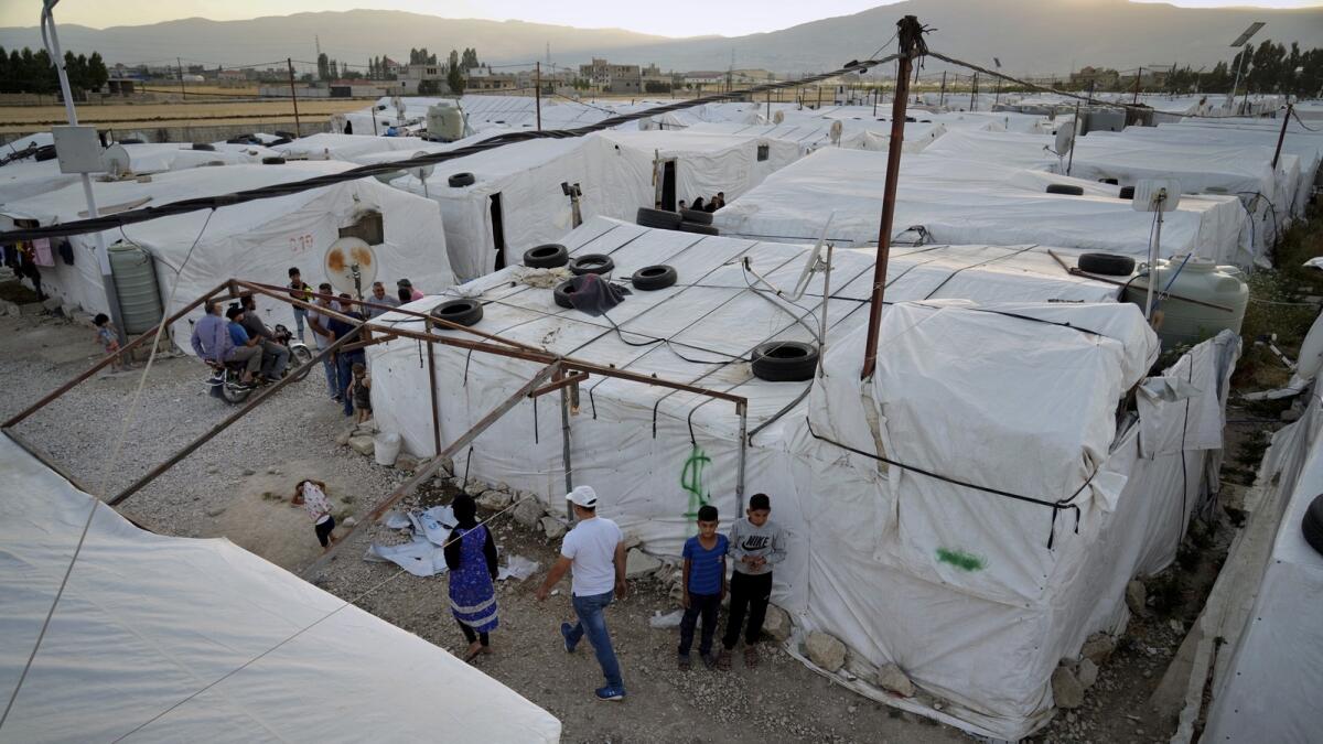 Syrian refugees walk by their tents at a refugee camp in the town of Bar Elias, in the Bekaa Valley, Lebanon. — AP file