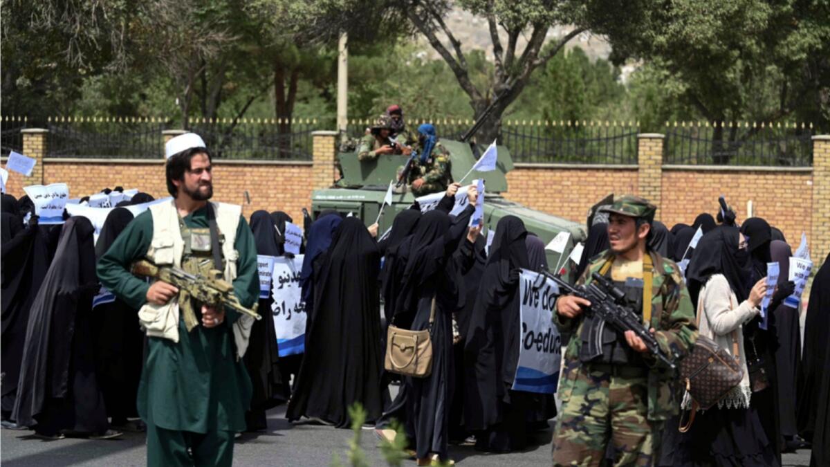 Armed Taliban fighters escort veiled women marching during a pro-Taliban rally outside Shaheed Rabbani Education University in Kabul. — AFP