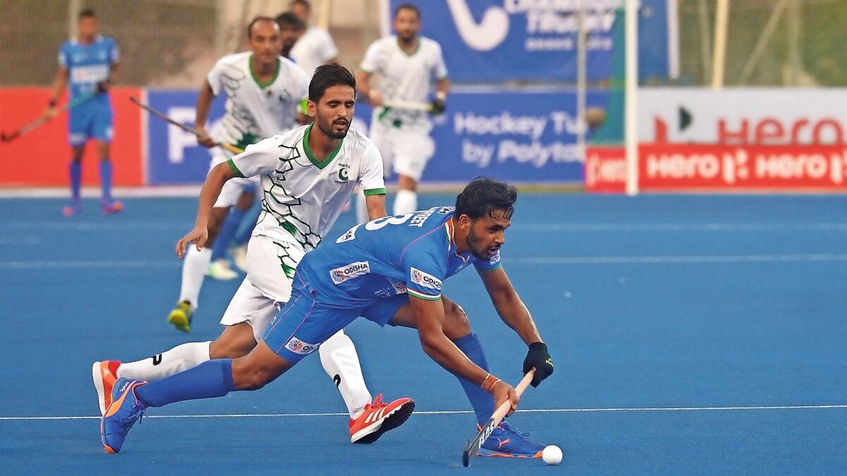 India's Harmanpreet Singh (right) dodges the ball past Pakistan's Ali Ghazanfar during the match against Pakistan on Friday. — AFP