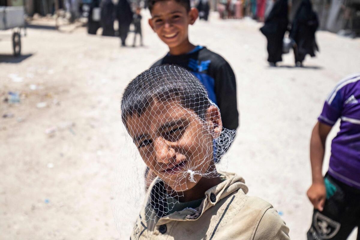 A boy poses with fishnet bag on his head at the Al Hol camp in Syria's northeastern Al Hasakah Governorate, on October 10, 2023. — AFP